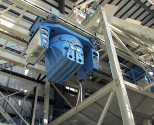 Fig. 7: One of four ﬂying buckets is poised below its mixer discharge gate awaiting the next batch of fresh dry cast mix